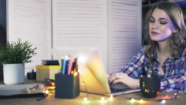 Pan schot van aantrekkelijke jonge vrouw die werkt op een laptop bij casual kantoor. — Stockvideo