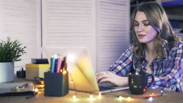 Pan tiro de mulher jovem trabalhando em um laptop no escritório casual . — Vídeo de Stock