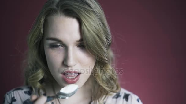 Close-up shot van de jonge vrouw die eten yoghurt en camera kijken. — Stockvideo