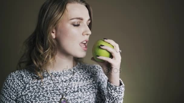 Un retrato de una joven mordiendo y comiendo sabrosa manzana verde — Vídeo de stock