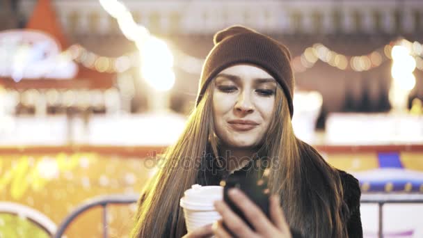 Vista frontal de una mujer con mensajes de texto de café en una ciudad nocturna — Vídeo de stock