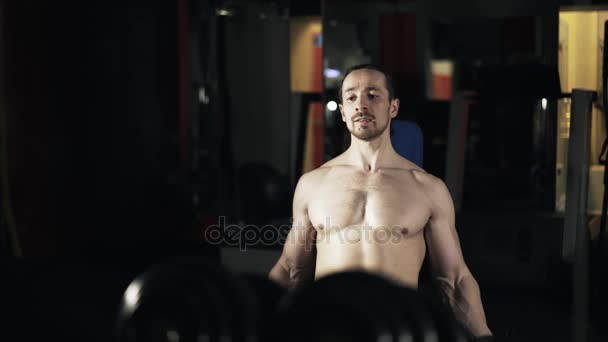Εμπρόσθια όψη ενός ανθρώπου με γυμνό τον κορμό που κάνει έναν αλτήρα άσκηση στο γυμναστήριο — Αρχείο Βίντεο