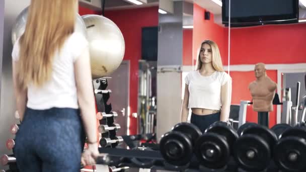 Riflessione di una donna che fa esercizio manubri in una palestra — Video Stock