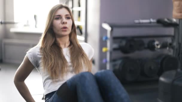Chica rubia haciendo ejercicios abdominales en un banco de gimnasia, de cerca — Vídeo de stock