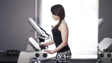 Genç kadın bir spor salonu, bir koşu bandı üzerinde yan görünüm