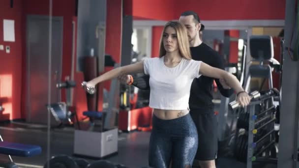 Treinador ajudando menina a fazer um exercício dumbbell — Vídeo de Stock