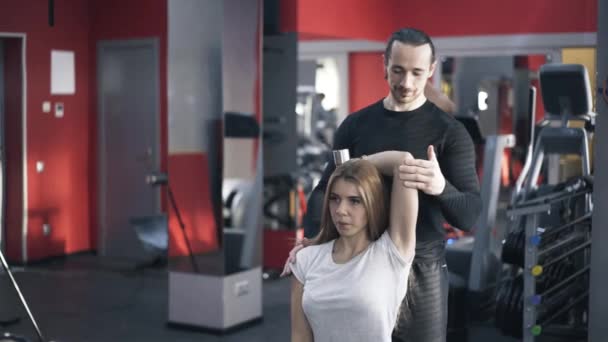 Kadın dumbbell egzersiz yapmak için yardımcı antrenör — Stok video