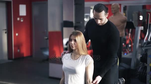 Entrenador está monitoreando a una mujer haciendo un ejercicio de mancuerna, inclinar hacia abajo — Vídeos de Stock