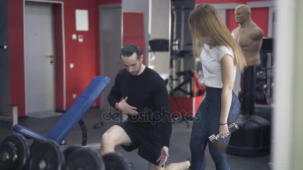 Coach mostrando donna come fare un esercizio in una palestra — Video Stock