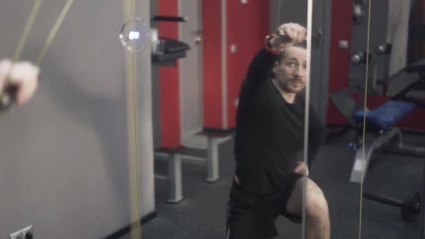 Jonge man tillen gewichten met de ene hand, vooraanzicht — Stockvideo