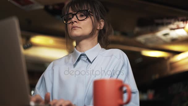 Mujer joven usando el ordenador portátil y beber café en un bar, toma de la cacerola — Vídeos de Stock