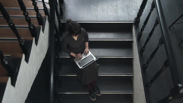 계단에서 노트북으로 작업 하는 젊은 여자의 상위 뷰 — 비디오