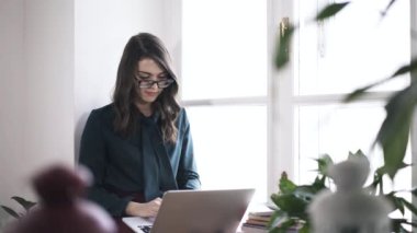 Laptop ile pencere kenarında, tilt çalışma aşağı gözlüklü genç kadın