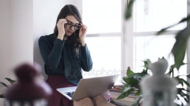 Gözlüklerini koyarak ve pencere laptop, tipik bir kadın
