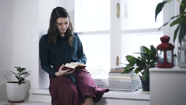 Mujer leyendo un libro en un alféizar de ventana — Vídeos de Stock