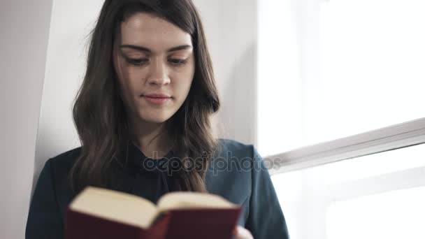 Молодая девушка читает интересную книгу — стоковое видео