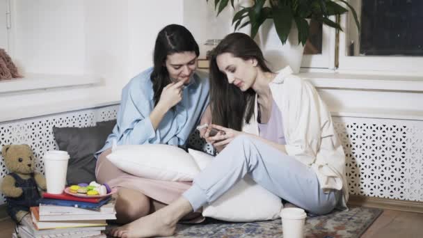Две женщины со смартфоном разговаривают дома — стоковое видео