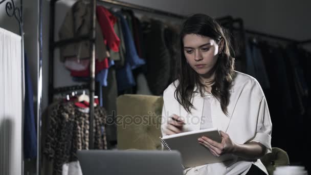 年轻女人看着手提电脑的屏幕和书写 — 图库视频影像