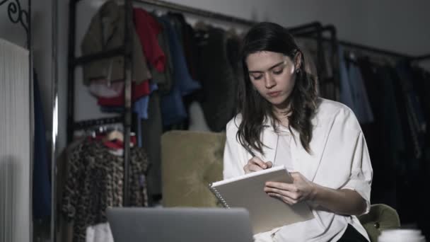 Chica joven mirando la pantalla del ordenador portátil y la escritura — Vídeo de stock