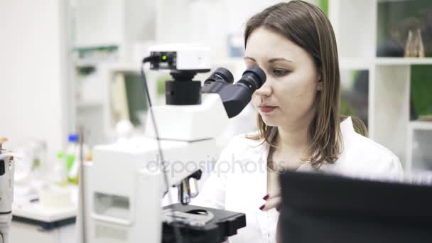 Vooraanzicht van vrouw wetenschapper met behulp van een Microscoop — Stockvideo
