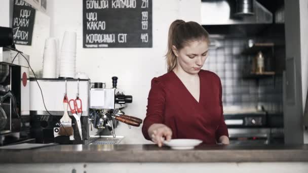 Kvinna barista sätter kaffe cup och tefat på counter — Stockvideo