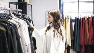 Genç kadın bir dükkanda giysiler seçmek
