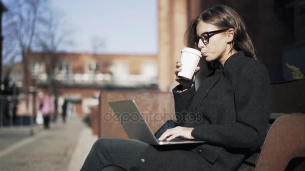 Vista lateral de una joven con un portátil en la calle — Vídeo de stock