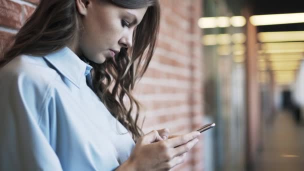 Jonge vrouw surfen netto met smartphone in de lobby van het kantoor — Stockvideo