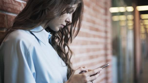 Jonge vrouw texting in de lobby van het kantoor — Stockvideo