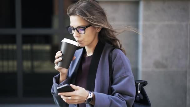 Женщина пьет кофе и разговаривает по телефону на улице — стоковое видео
