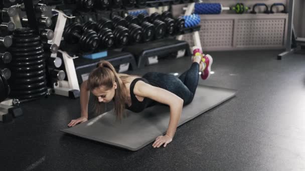 Mujer joven haciendo flexiones en un gimnasio — Vídeos de Stock