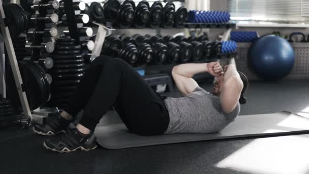 Muskulös ung man gör crunches i ett gym — Stockvideo