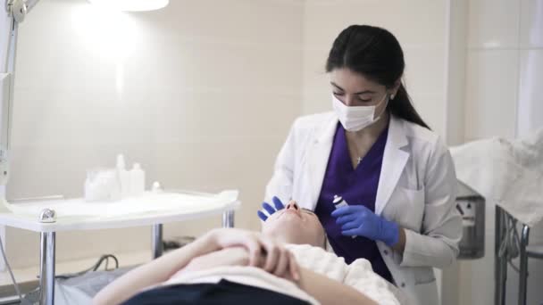 Kosmetikerin cremt die Stirn der Frau ein — Stockvideo