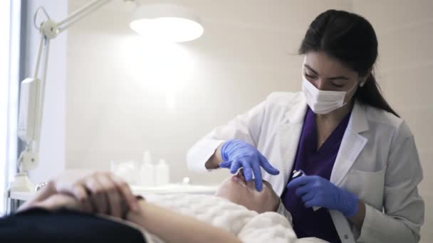 Cosmetician aplicação de creme para as bochechas da mulher, câmera lenta — Vídeo de Stock