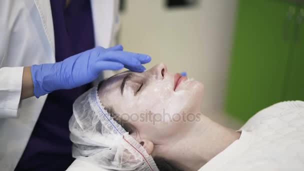 Косметик наносит крем на лицо женщины — стоковое видео