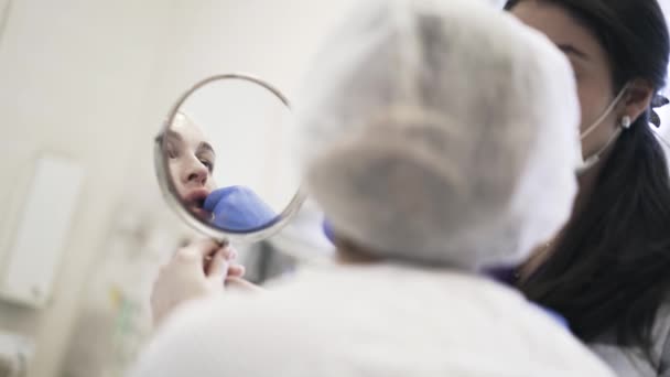 Mujer mirando en el espejo después de inyecciones de labios en el salón — Vídeo de stock