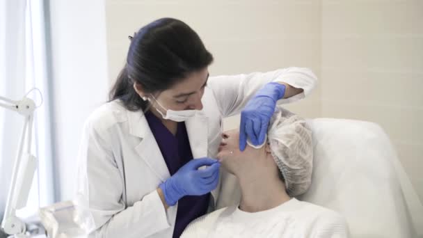 Kosmetikerin steckt Nadel in Wange — Stockvideo
