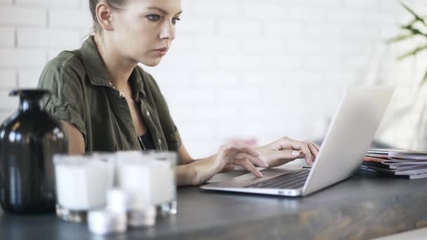 Νεαρή γυναίκα πληκτρολογώντας στο φορητό υπολογιστή στο γραφείο, κλίση — Αρχείο Βίντεο