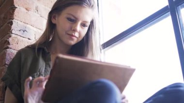 Gülümseyen pencere yakınındaki tablet ile genç kadın