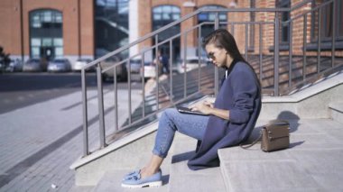 Sokakta merdivenlerde kadın dizüstü bilgisayar ile yan görünüm