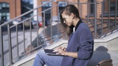 Merdivenlerin üstünde laptop ile gülümseyen kadın