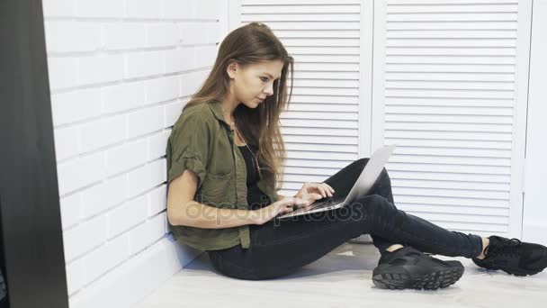 Jonge vrouw achter laptop op de verdieping, pan schot te typen — Stockvideo