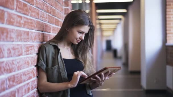 Jonge vrouw met een tablet in de bandbreedte van het kantoor, pan schot — Stockvideo