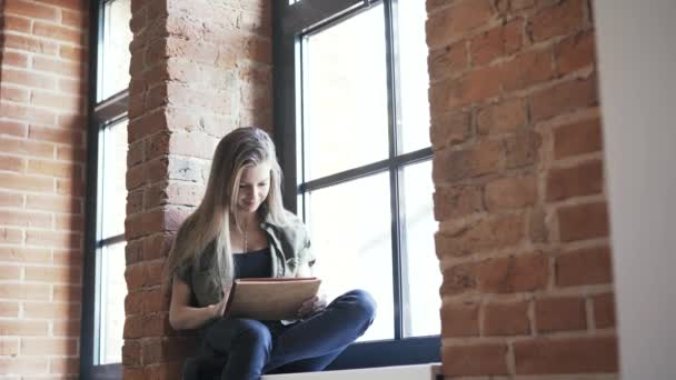 Jonge vrouw met tablet op de vensterbank, kantelen naar beneden — Stockvideo