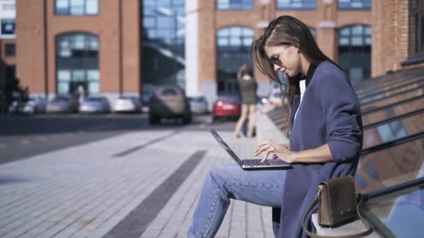 Seitenansicht eines jungen Mädchens mit einem Laptop auf der Straße — Stockvideo