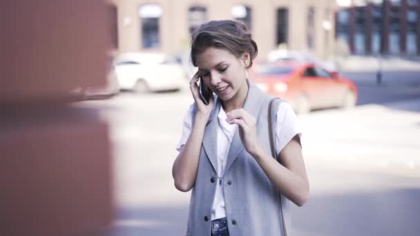 Νεαρή γυναίκα που μιλάτε στο τηλέφωνο στο δρόμο — Αρχείο Βίντεο
