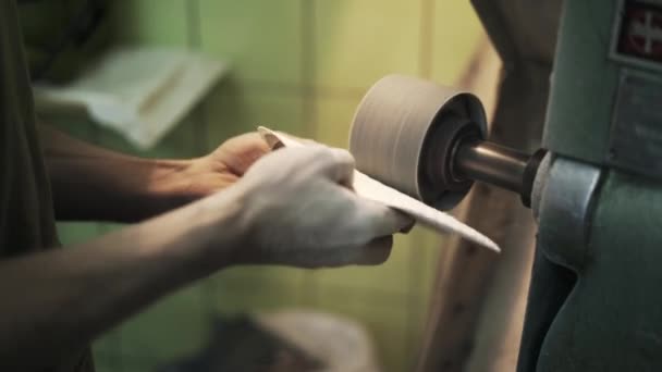 Gros plan des mains du cordonnier avec des couches de tissu blanc sur la ponceuse 
