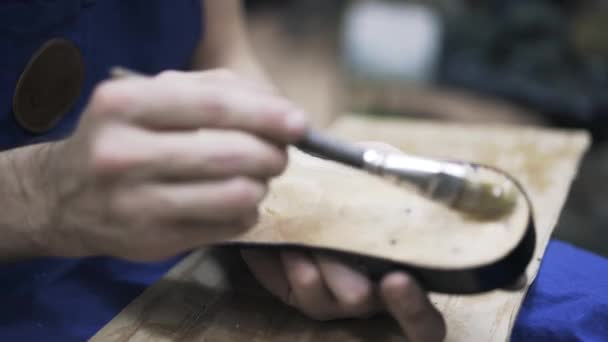 Cobbler aplicando pegamento en la suela de la bota del hombre — Vídeo de stock