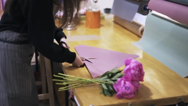 Primer plano de las manos de la mujer envolviendo un ramo de flores en una tienda — Vídeo de stock