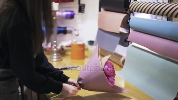 Zijaanzicht van vrouw s handen een bloemboeket verpakken in een winkel — Stockvideo